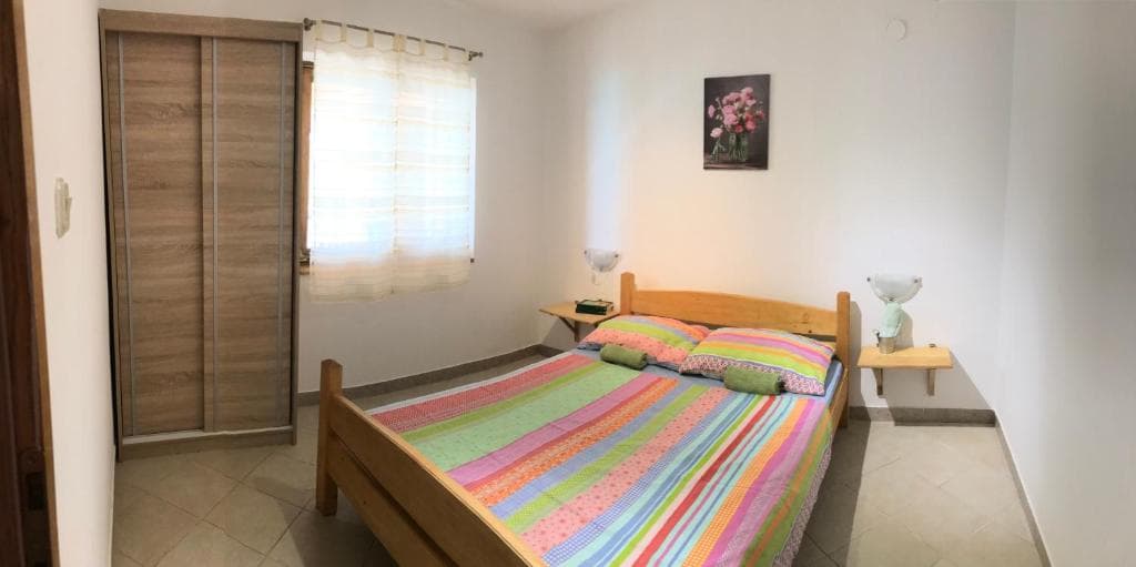Spavaća soba s drvenim krevetom i šarenim prekrivačem